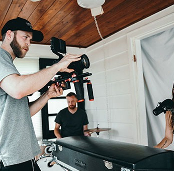 A Man And Woman Are Filming A Video Together In A Well-lit Room, Surrounded By Cameras And Recording Equipment.