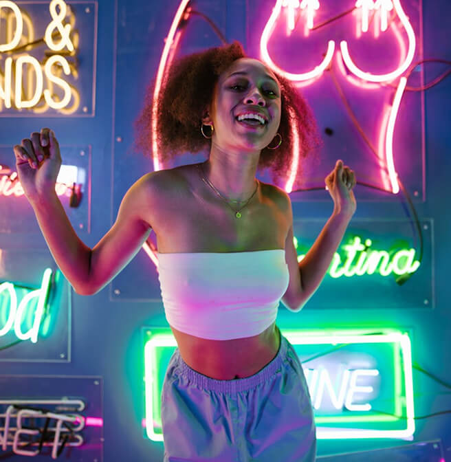 Woman Standing Before Vibrant Neon Lights In A Colorful Urban Setting
