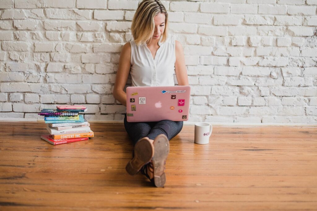 Woman Sitting On The Floor, Focused On Her Laptop In A Cozy, Relaxed Environment